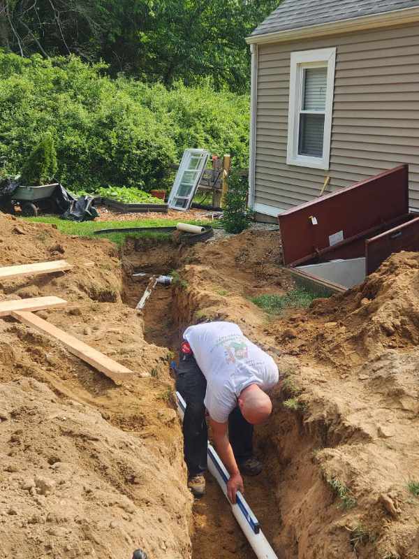 Construction worker in ditch laying underground pipes.